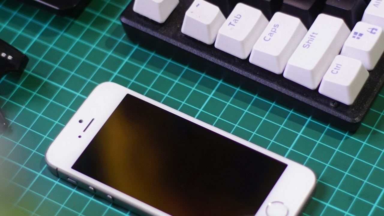 Smartphone, keyboard and laptop on a desk